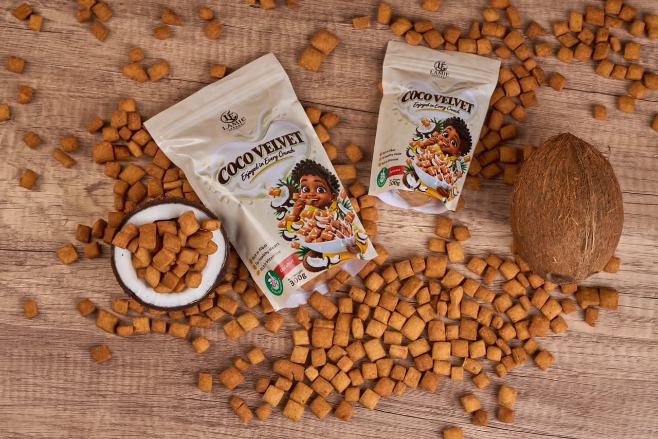 Two Coco Velvet chinchin pouches with a coconut and scattered chinchin on a wooden table